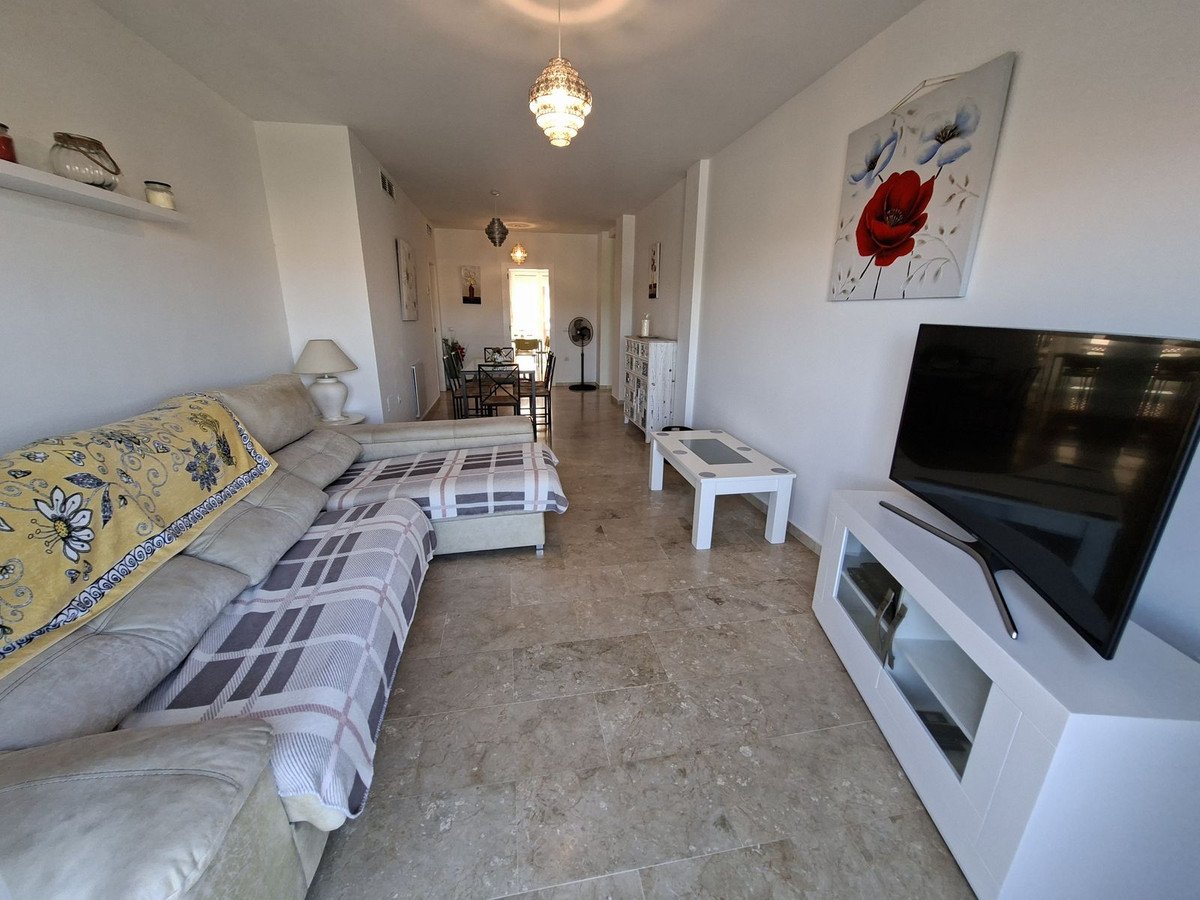 Spacious living room with a sectional sofa, coffee table, TV, and a glimpse of a dining area in the background.