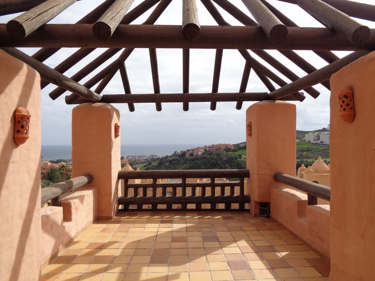 Terrace with sea and coastal town view, featuring wooden pergola and terracotta tiles.