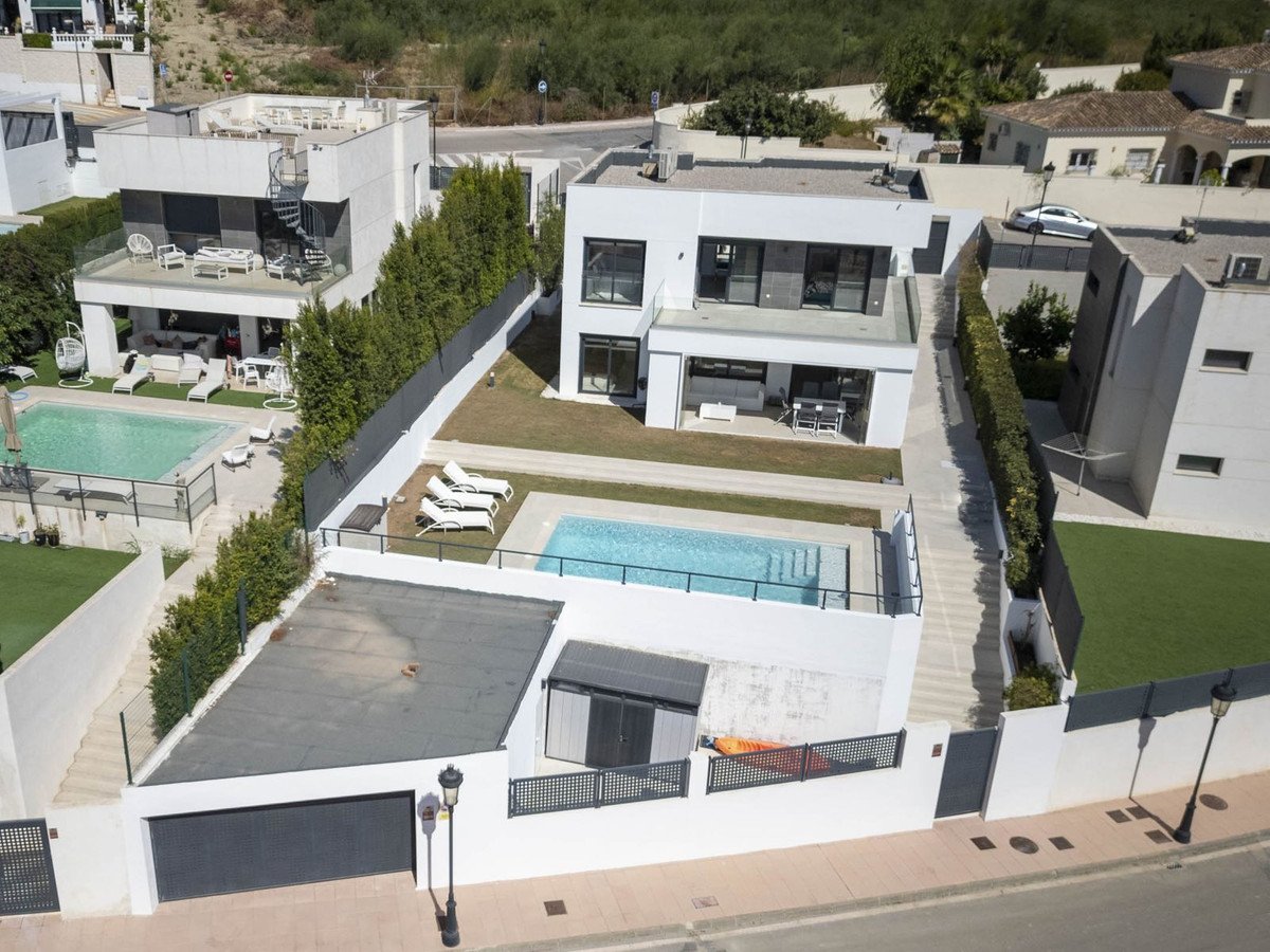 Modern villa with swimming pool, lounge area, and sunbeds. Outdoor terrace and garden spaces visible.