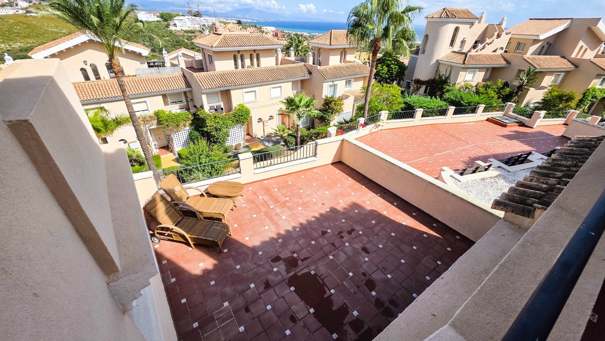 Spacious tiled terrace with lounge chairs, overlooking the sea and lush greenery, offering a serene outdoor living space.