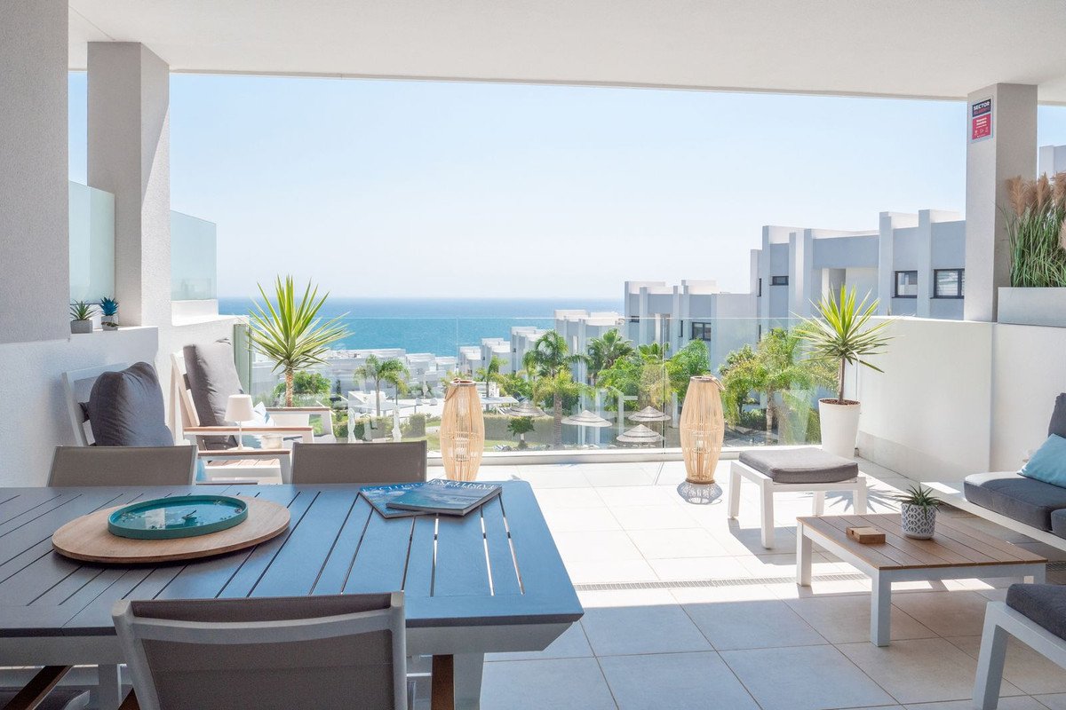 Modern terrace with seating area, outdoor dining table, and a stunning sea view.