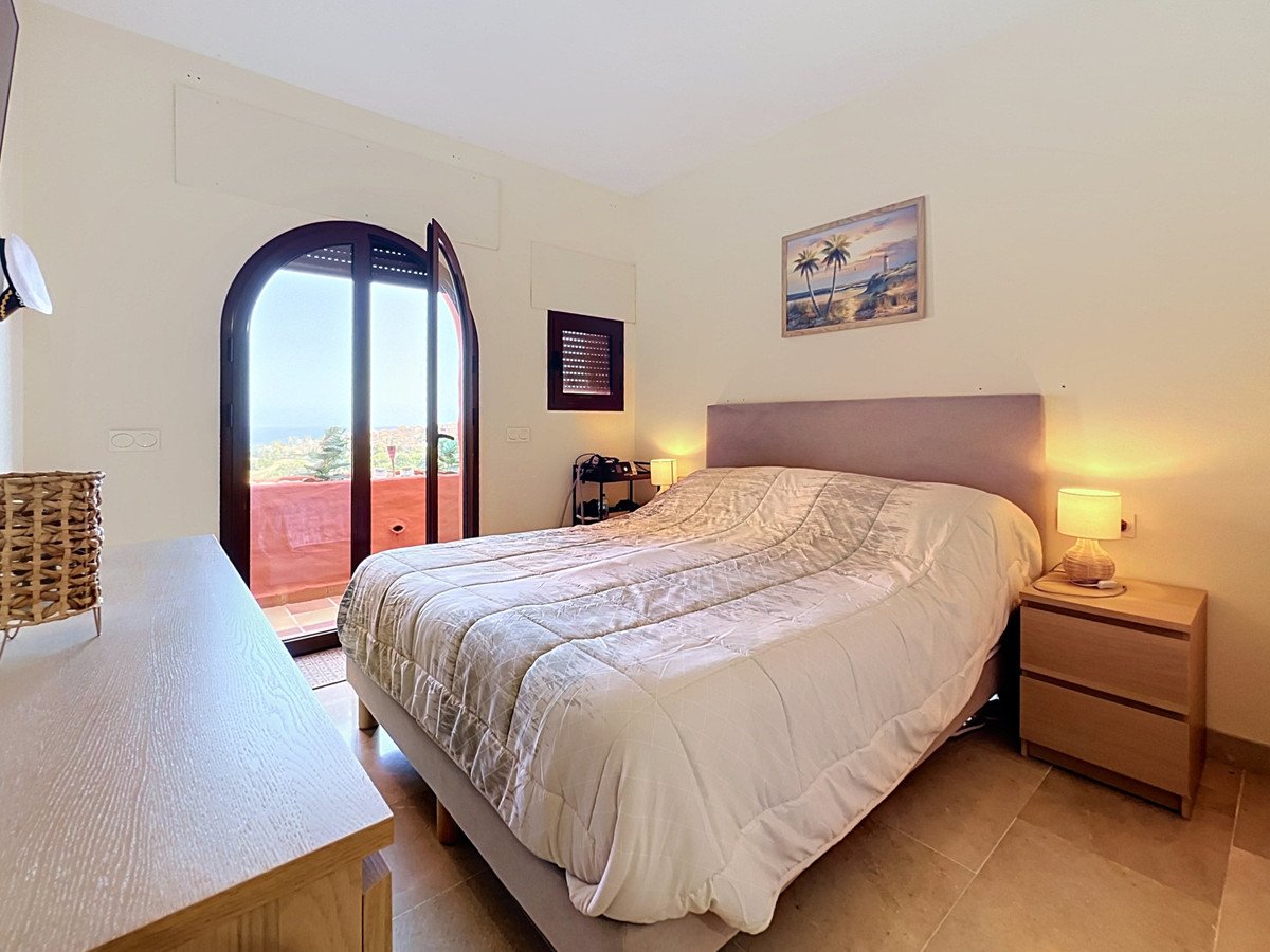 Cozy bedroom with large bed, nightstands, and a view of the sea through arched doors