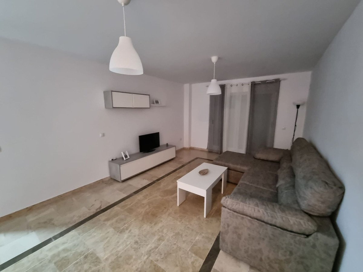 A modern living room features a grey sectional couch, white coffee table, TV, and a wall-mounted media unit with marble floors of marble tiles.