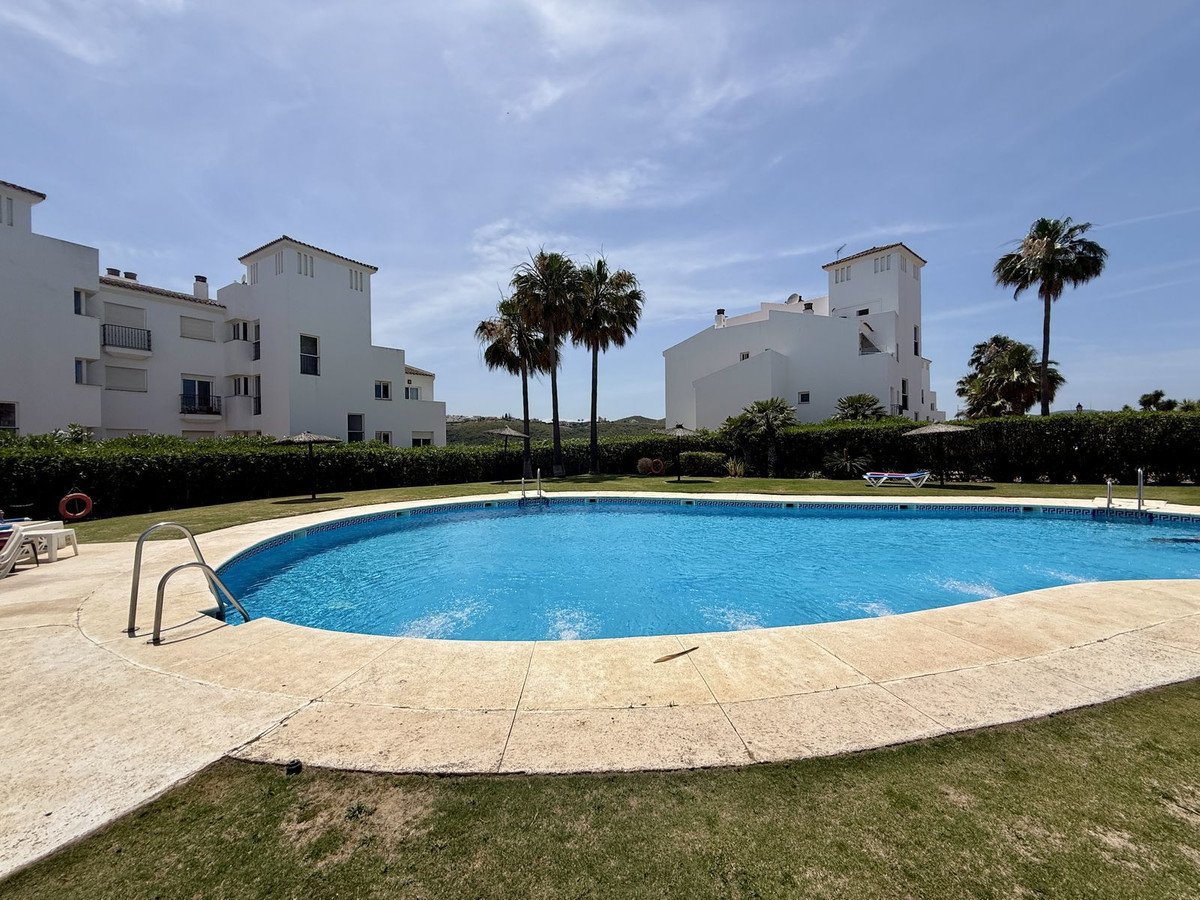 Villa mit privatem Pool, Palmen und weißen Gebäuten unter blauem Himmel.