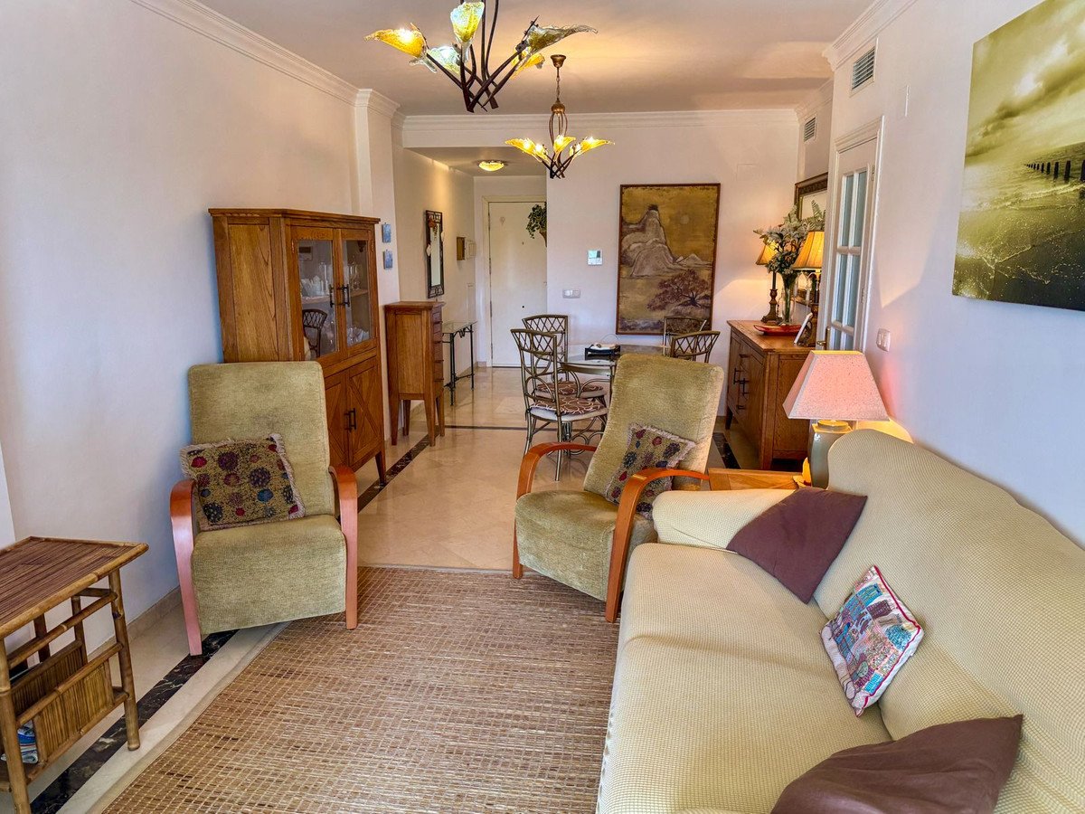 Wohnzimmer mit beigem Sofa, Holzmöbeln, Kristallleuchtern, Durchgang zum Essbereich.