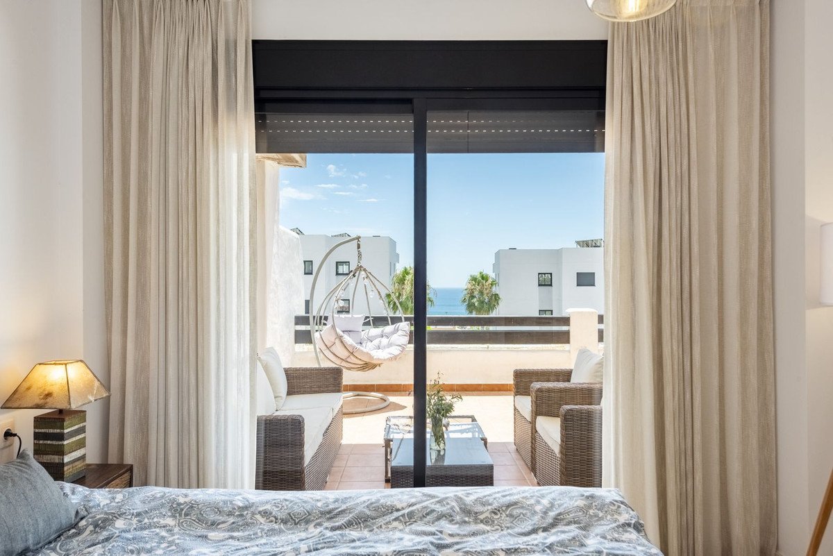 Balcony with sea view through large glass doors, featuring a hammock and outdoor furniture