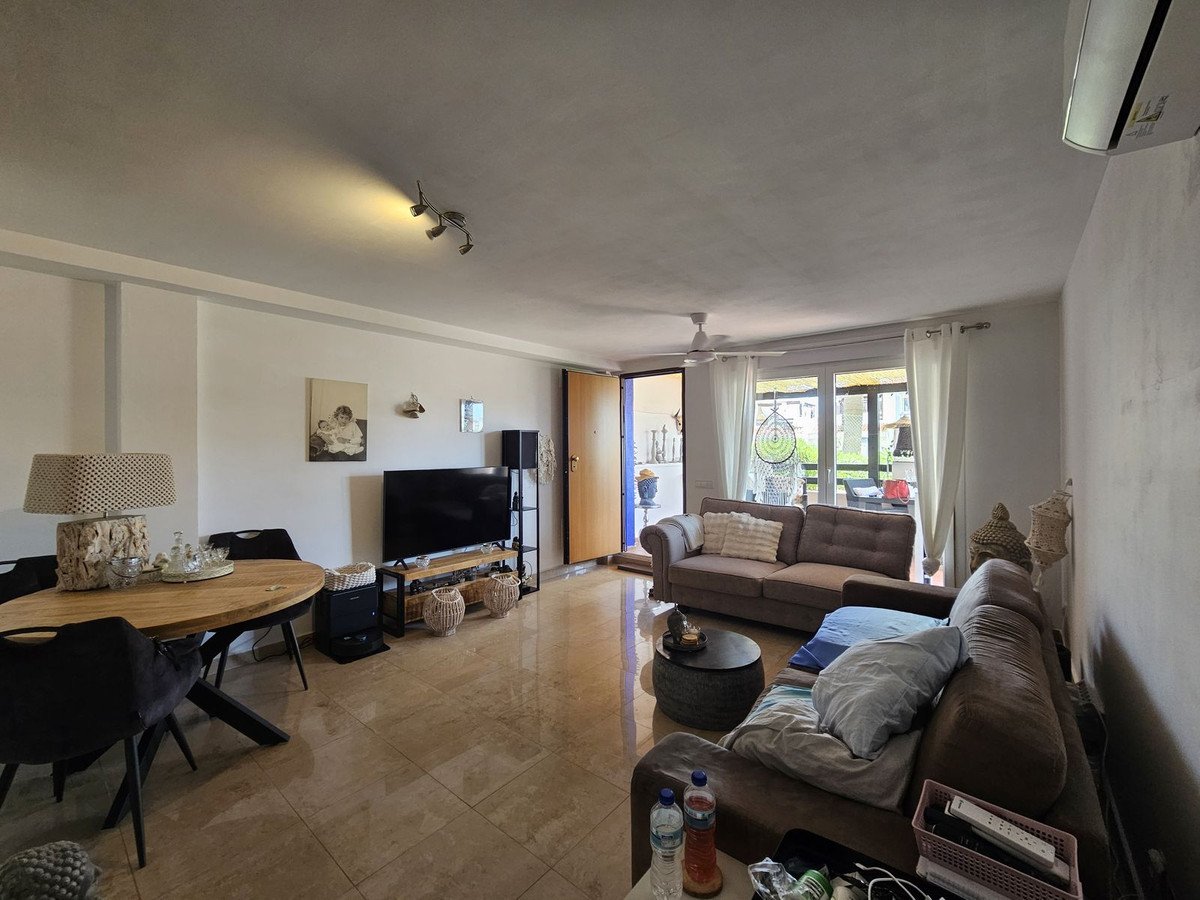 Spacious living and dining area with comfortable sofas, a television, and a view to an outdoor space.