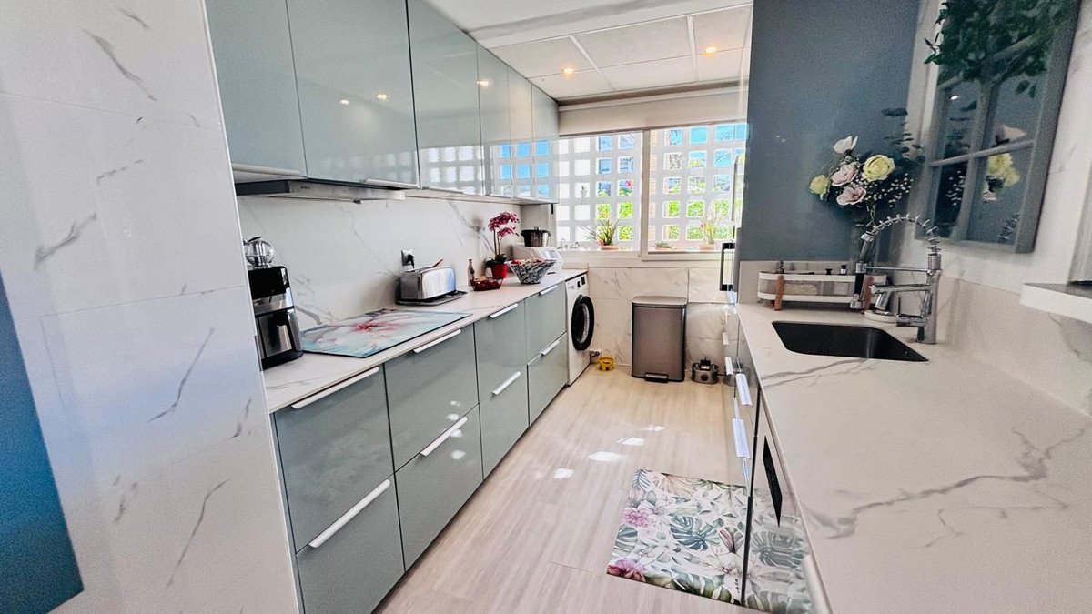 Modern kitchen with marble countertops, large window, and stainless steel appliances