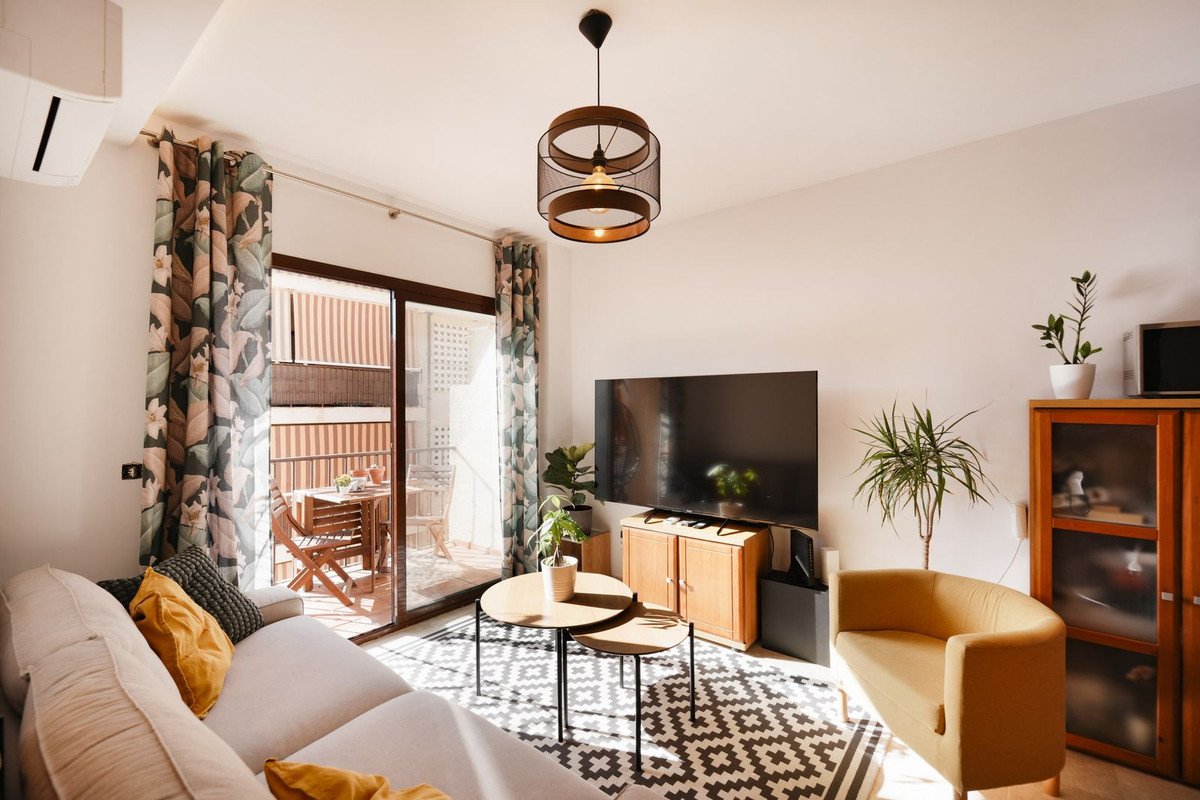 Moderne woonkamer met balkon uitzicht, vloerkleed, gele fauteuil en tv.