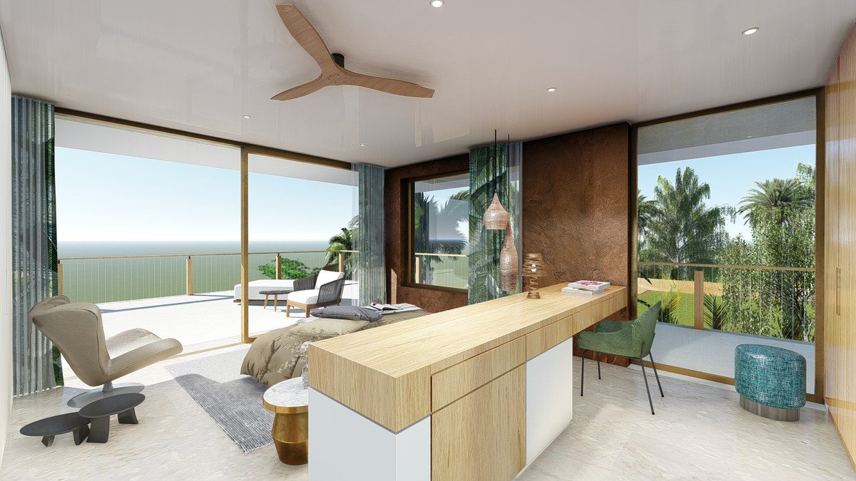 Modern bedroom with a desk, seating area, and a balcony offering a stunning sea view and lush greenery.
