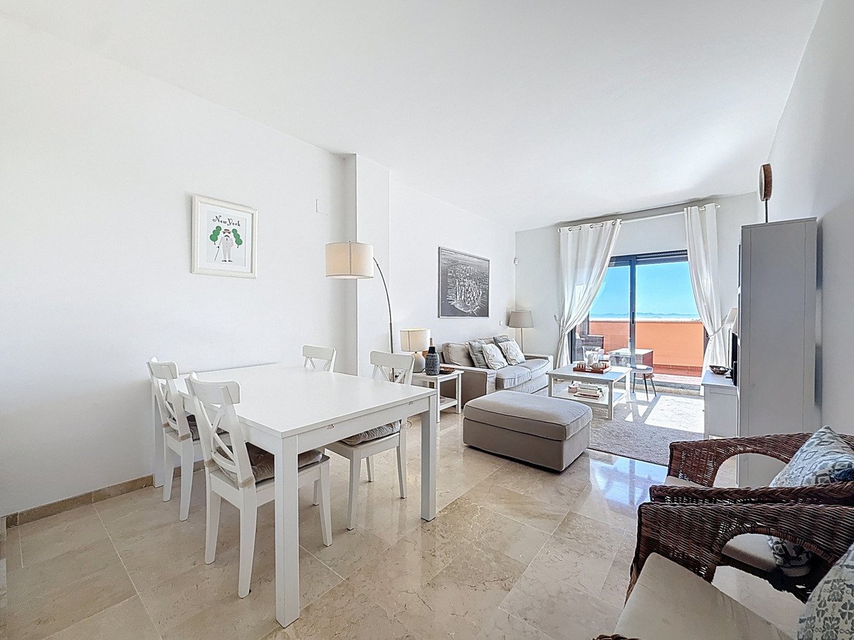 A bright living and dining area with a large balcony offering a beautiful sea view.