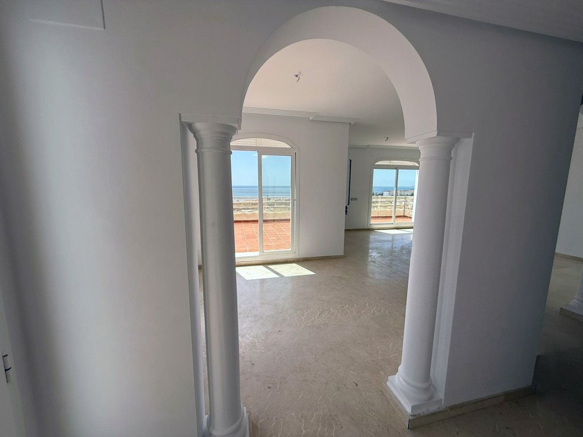 Arched corridor with marble flooring leading to a room with sea view through glass doors
