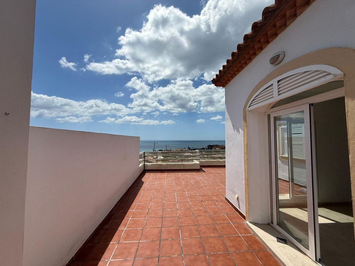 Balcony with terracotta tiles, sea view, and cloudy sky