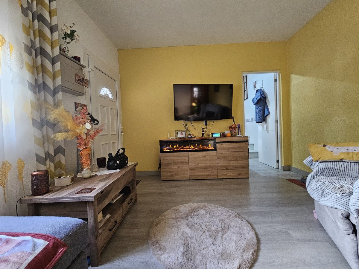 Cozy living room with yellow walls, fireplace, TV, and a large fluffy rug