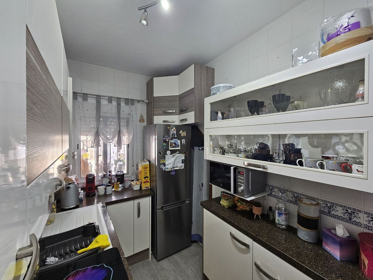 Modern kitchen featuring white cabinets, stainless steel appliances, and a variety of kitchenware on open shelves