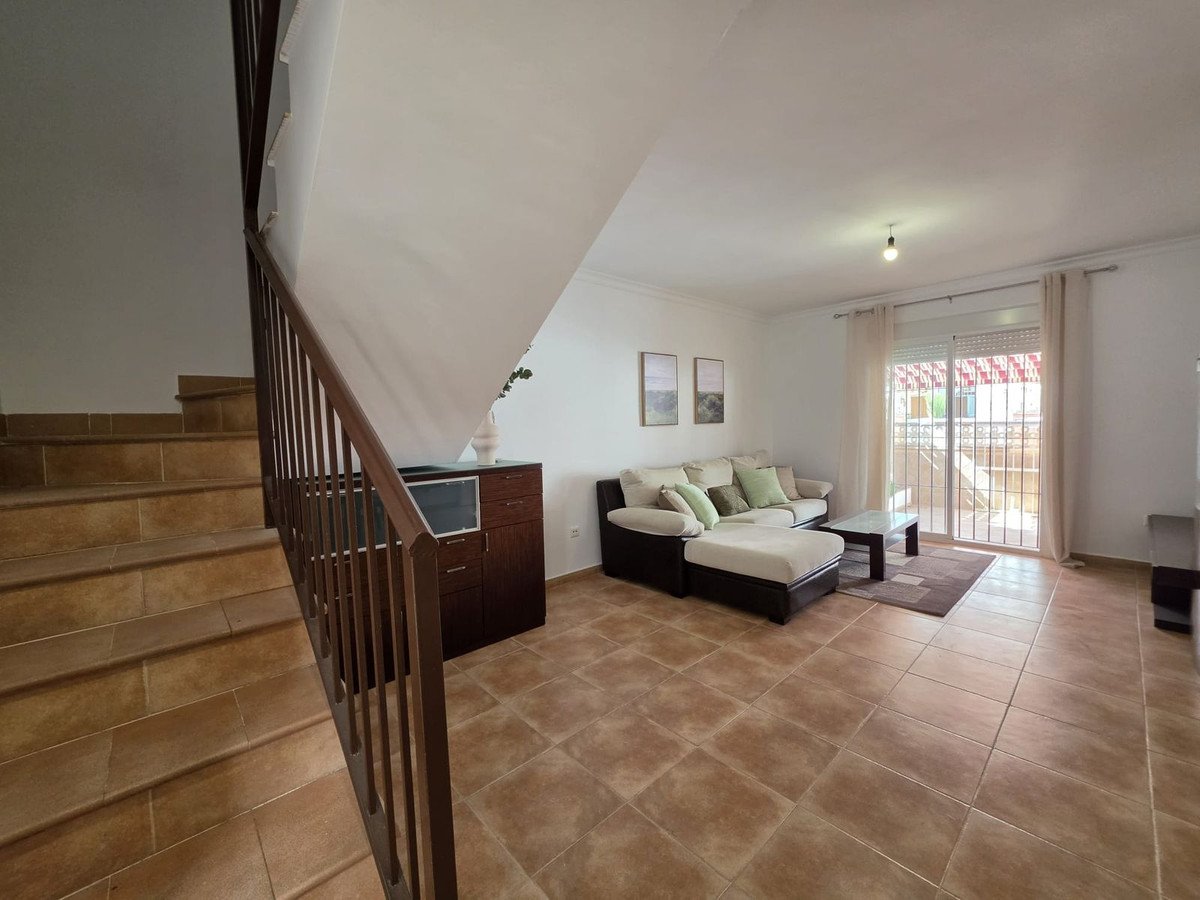 Living room with beige sofa, tiled floor, and large window with curtains