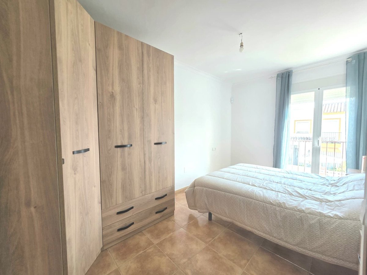 Spacious bedroom with wooden wardrobe, tiled floor, and balcony view.