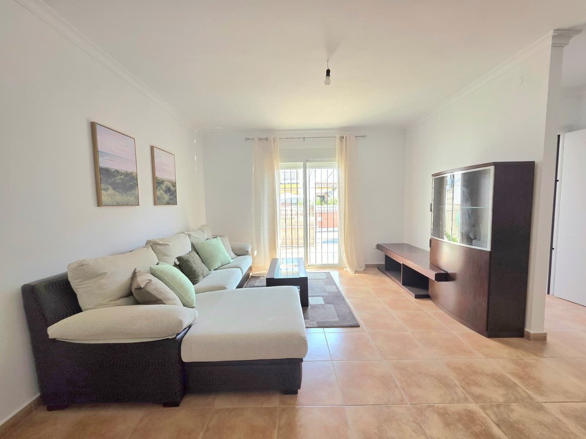 Living room with beige sofa, paintings on the wall, and a view through the window