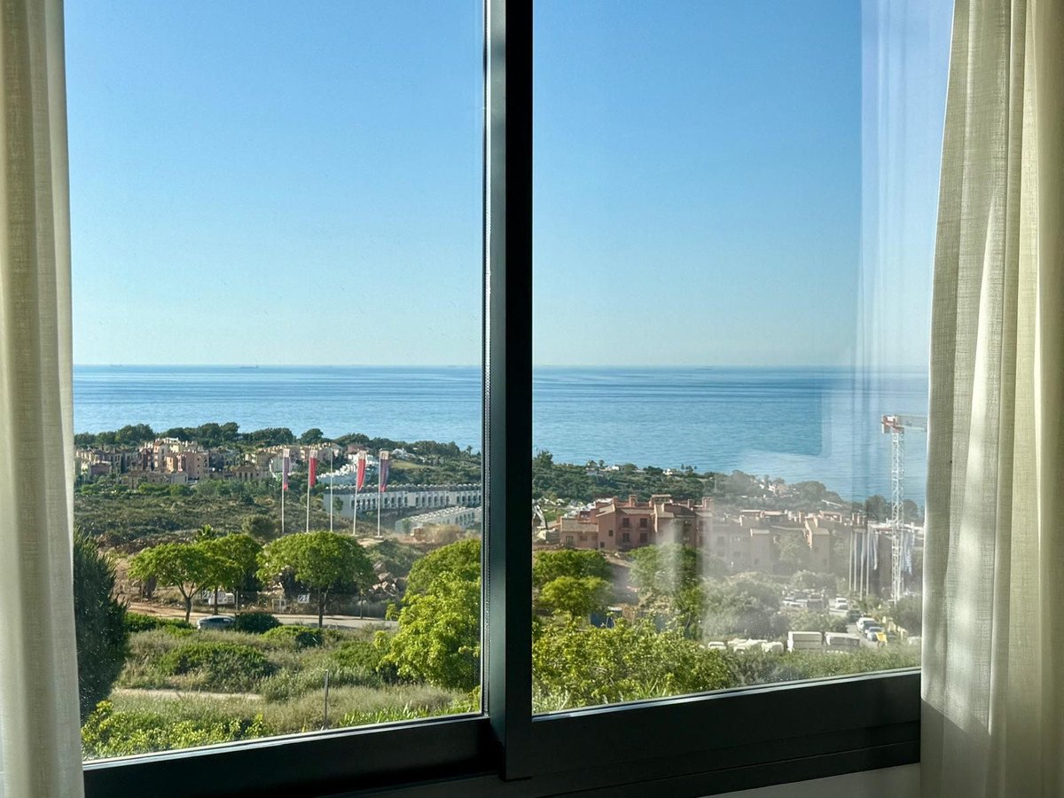 Ocean view through large window with curtains and coastal town below