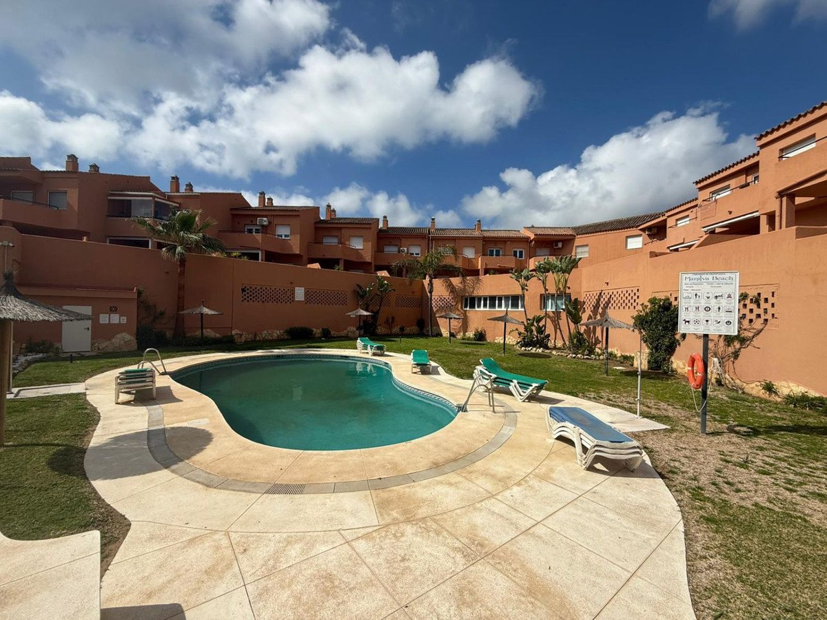Large kidney-shaped swimming pool with lounge chairs and terracotta buildings in the background