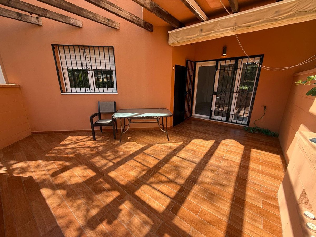 Sunlit terrace with wooden table, chairs, and large windows