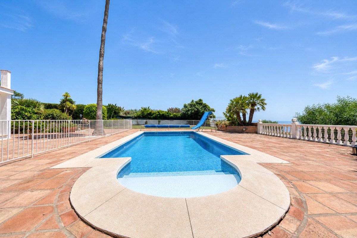 Villa with private pool, slide, and ocean view under clear blue sky.