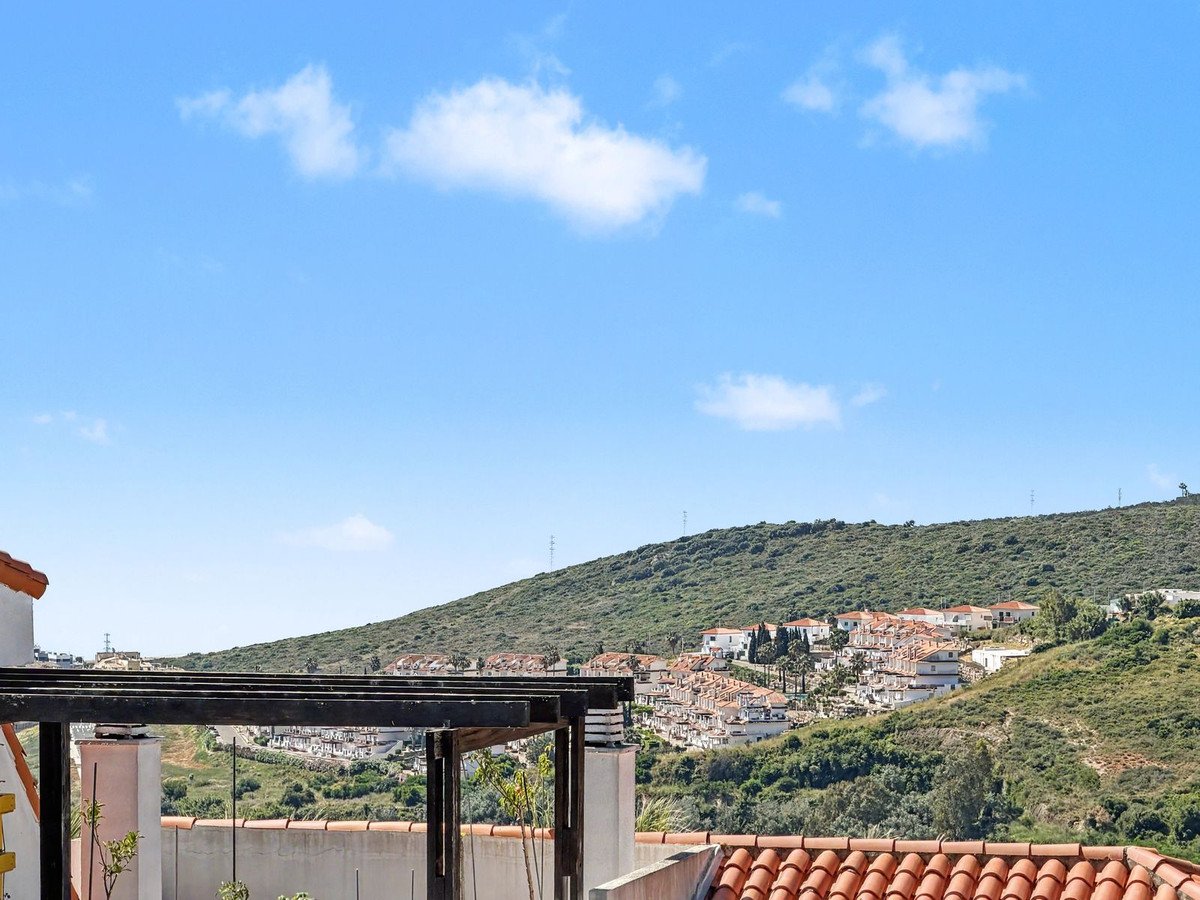 Balcony view of a hillside village with terracotta roofs under a blue sky.