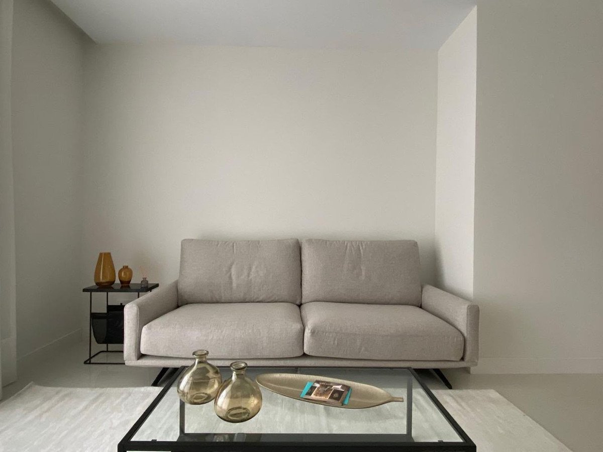 A neutral-toned sofa and glass coffee table with decorative vases in a modern living room.