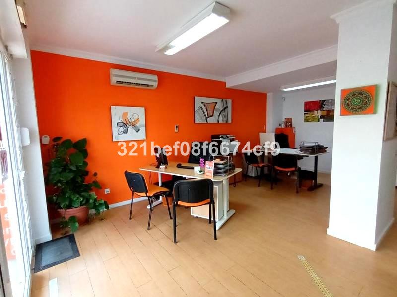 Modern office with desks, orange accent wall, and artwork. Includes a plant and view of the interior workspace.