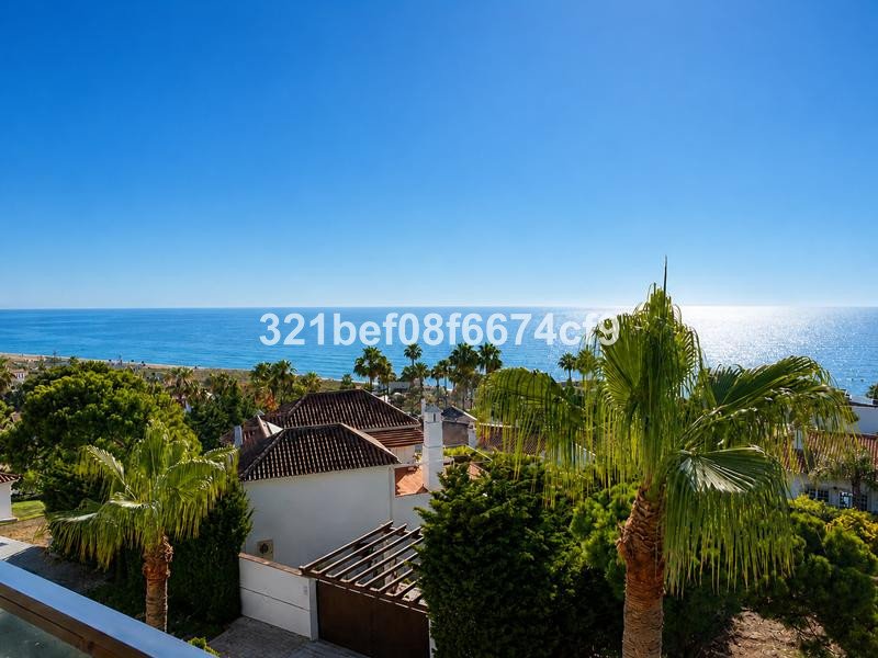 A stunning sea view from a balcony with palm trees and rooftops below under a clear blue sky.