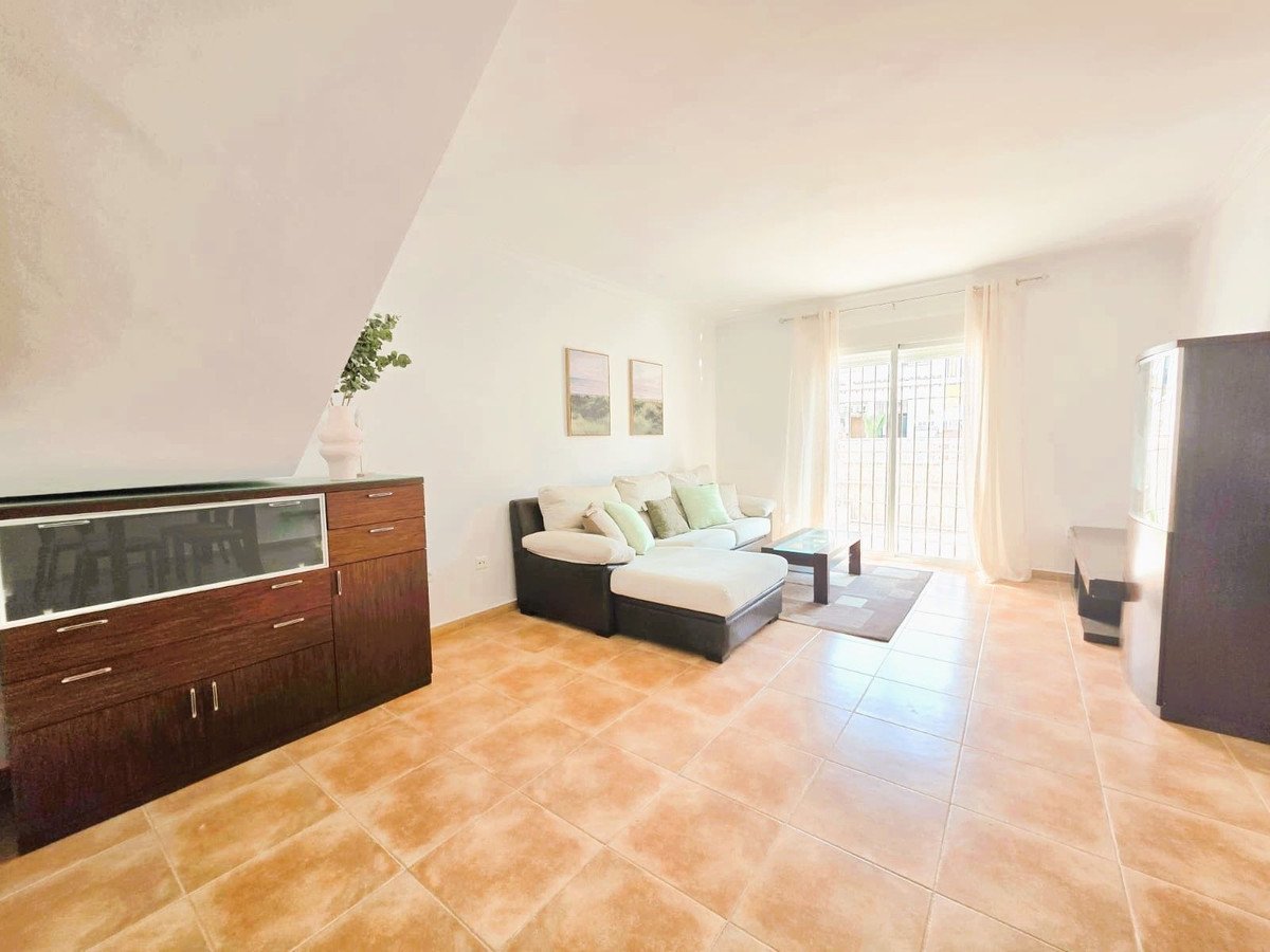 A spacious living room features a sectional couch, coffee table, and a sliding glass door leading to an outdoor space.