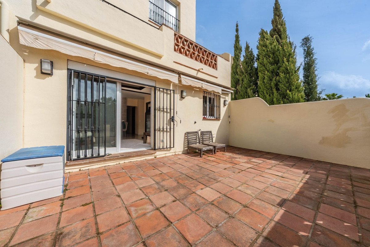 Courtyard with patio furniture, glass doors, and a view of tall trees.