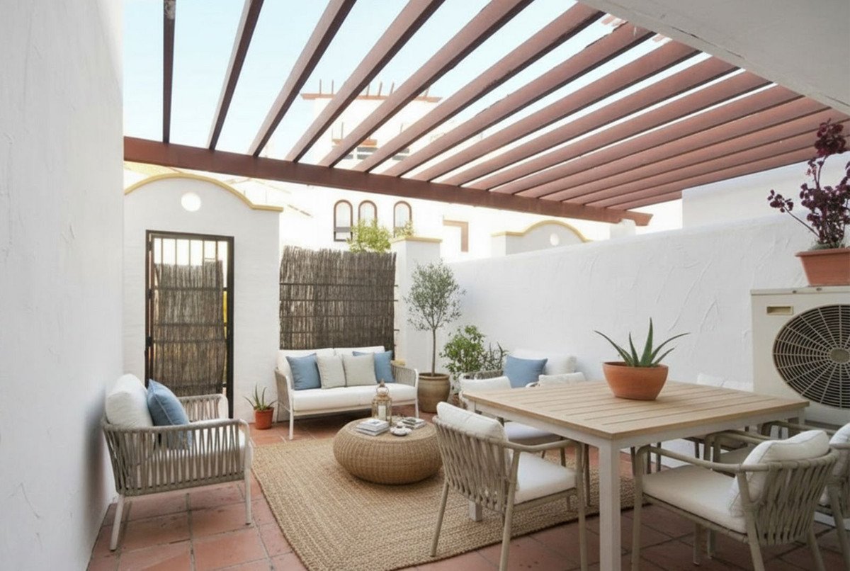 Covered patio with wooden pergola, white furniture, and potted plants.