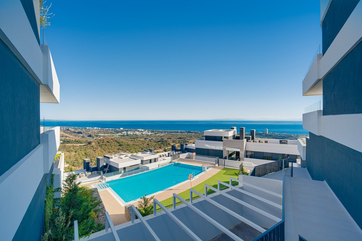 Modern complex with swimming pool and sea view on a sunny day.