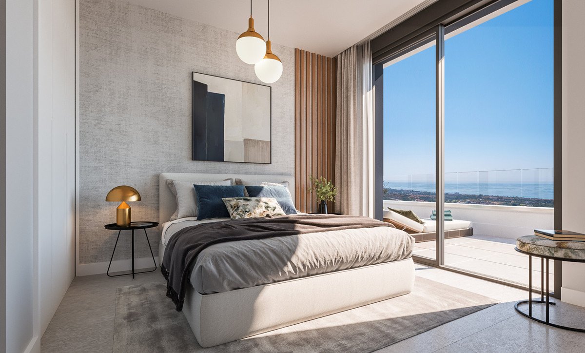 Modern bedroom with a large bed, facing a balcony with a beautiful sea view and clear blue sky.