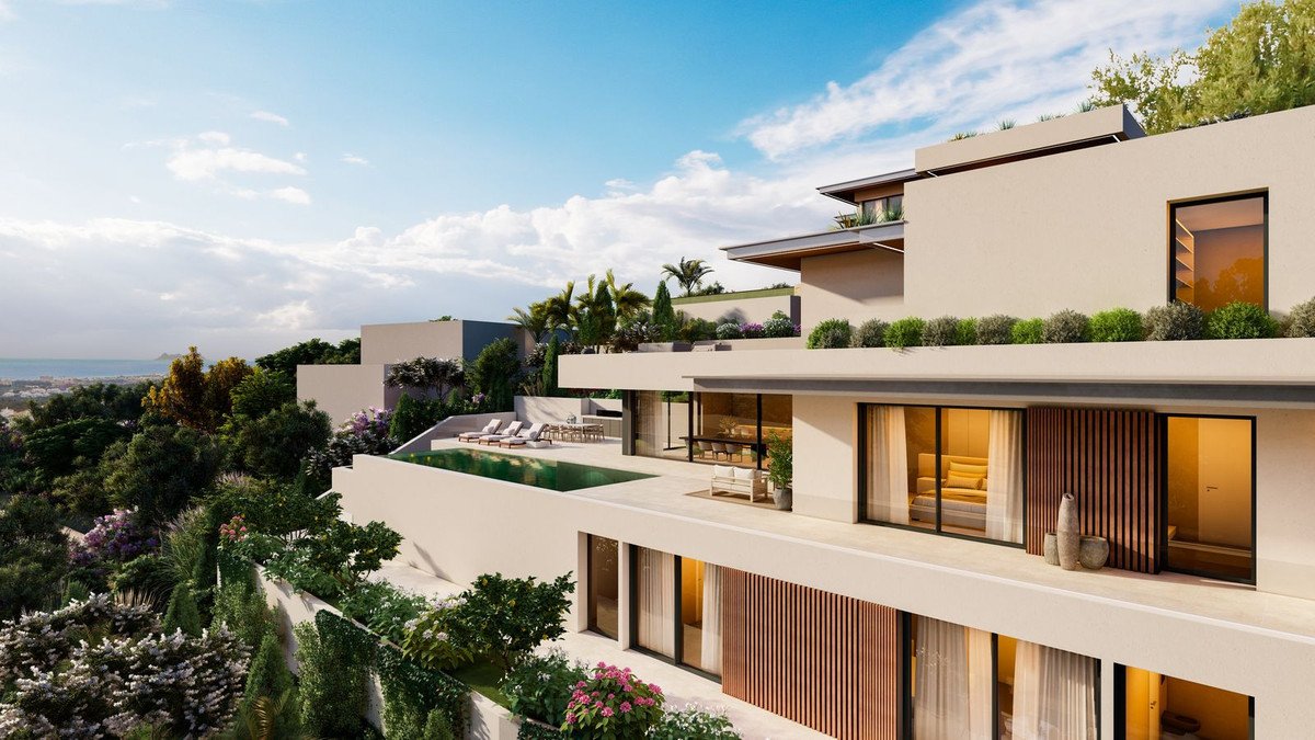 Modern villa with infinity pool overlooking the sea, surrounded by lush greenery and trees.