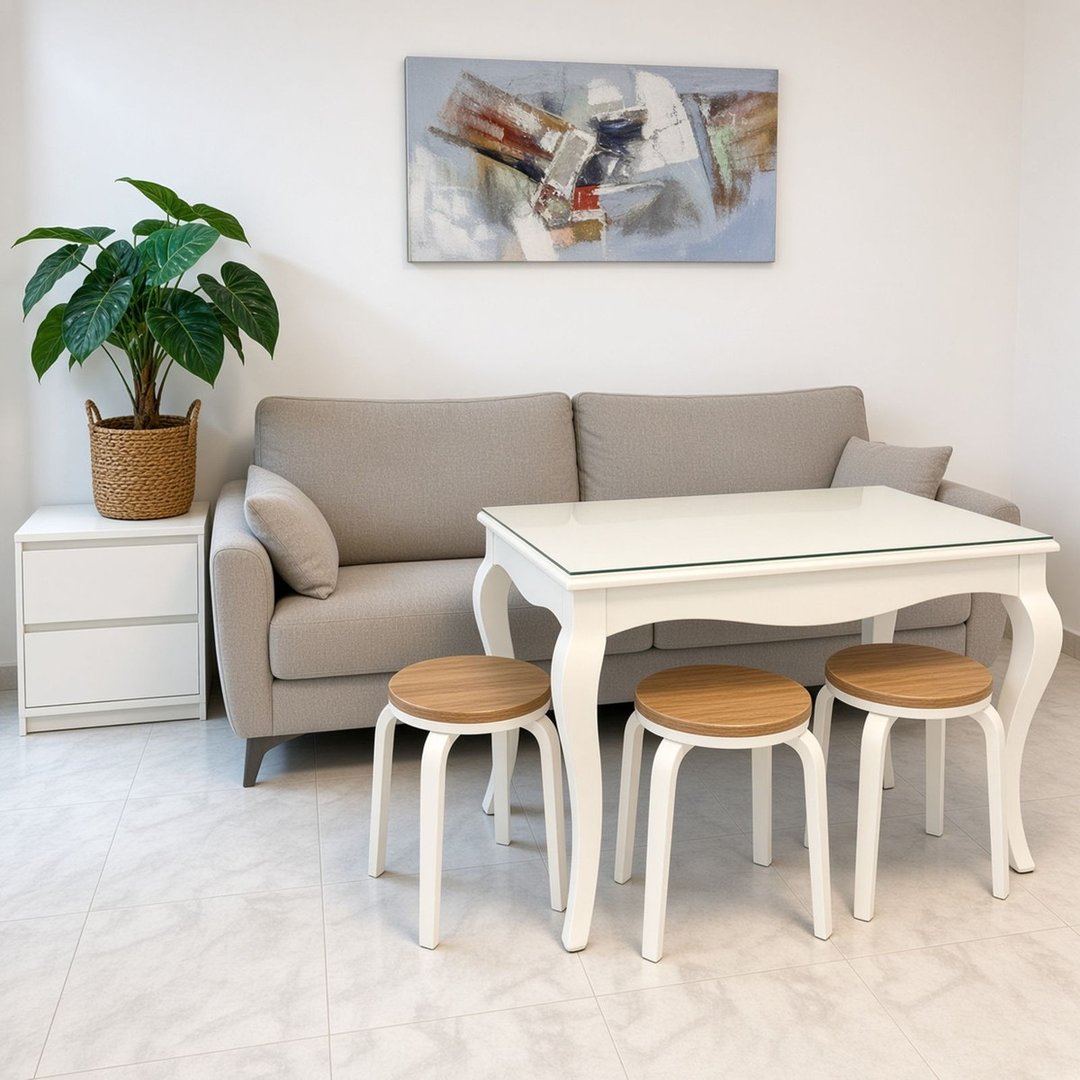 A bright living area with a sofa, white table, three stools, and a plant.