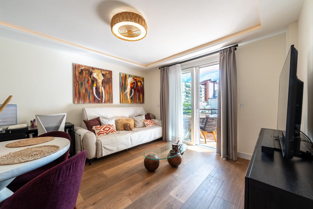 Living room with a sofa, modern art, and balcony access with a city view beyond the sliding glass doors.
