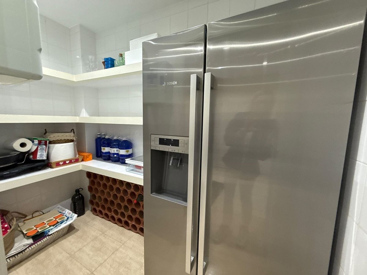 Kitchen with stainless steel fridge, shelves, and tiled floor
