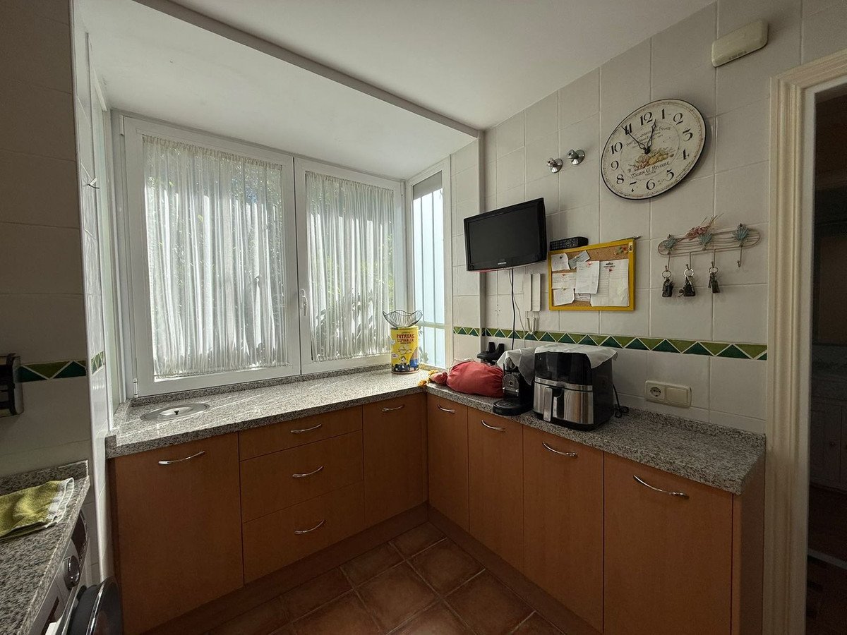 A kitchen with a window, granite countertops, and wooden cabinets.
