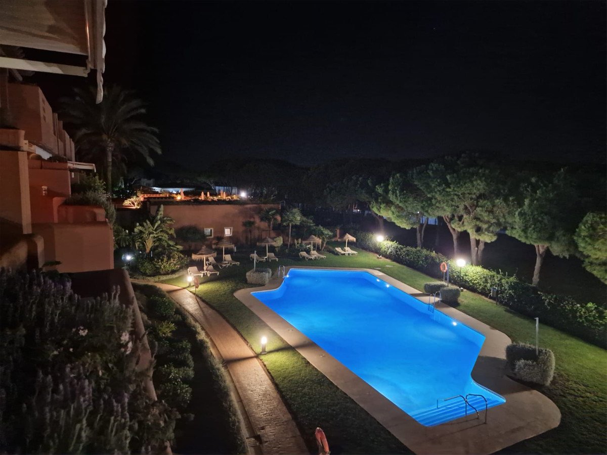 Night view of a lit swimming pool with outdoor seating and landscaping