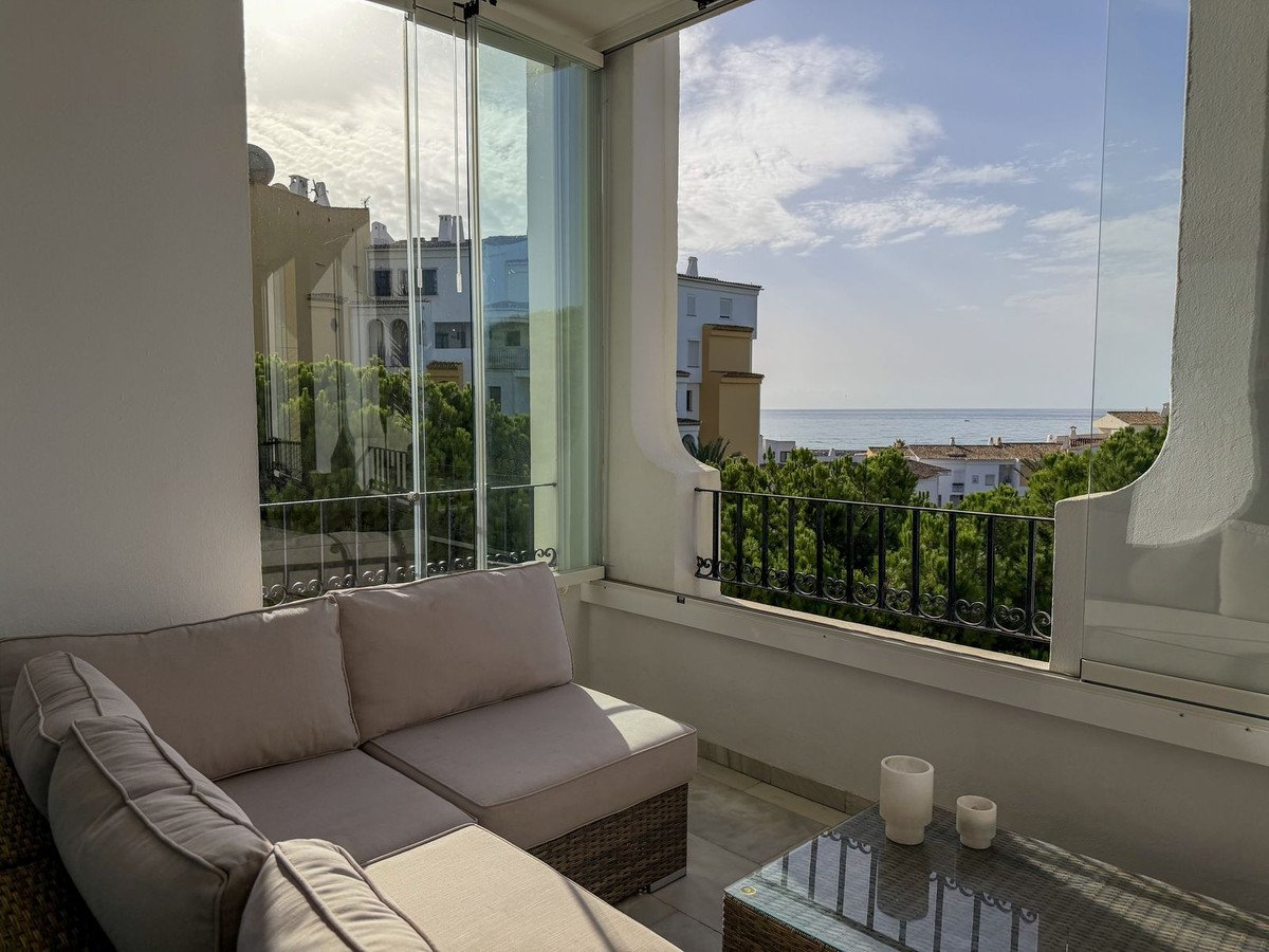 Balcony with lounge seating overlooking sea and buildings