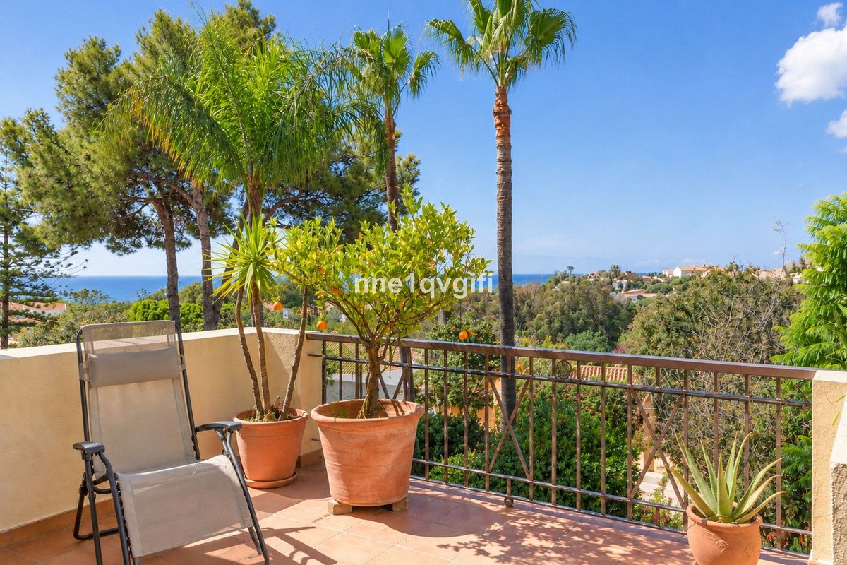 Terrace with sea view, palm trees, orange tree, and a lounge chair.