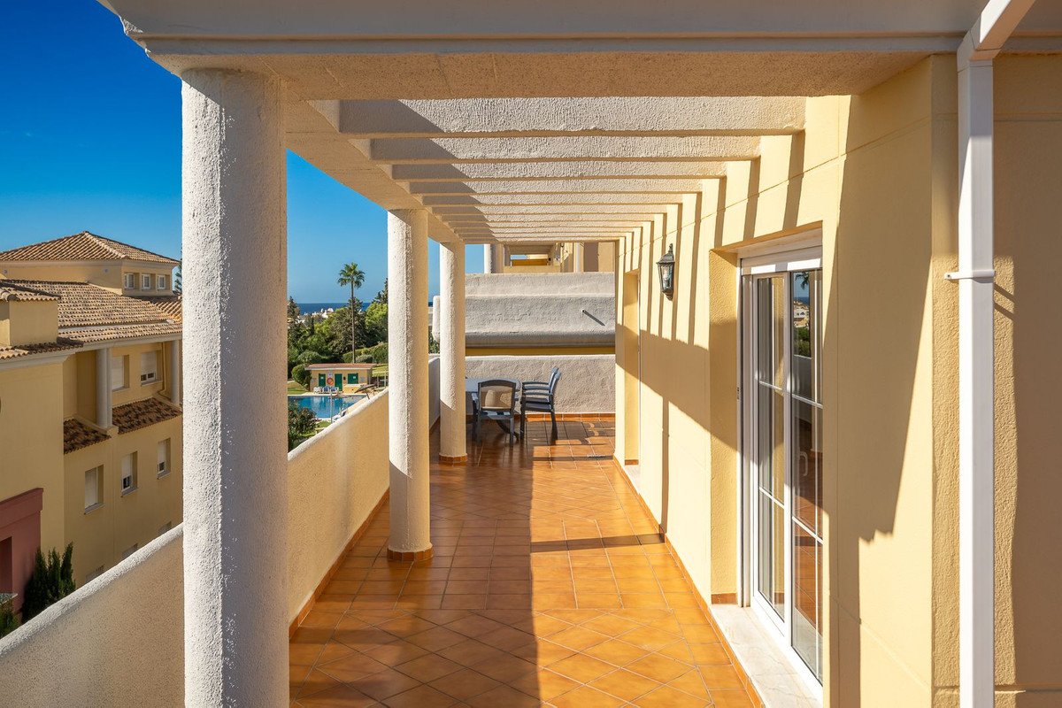 Balcony with tiled floor, outdoor seating, and view of sea and buildings