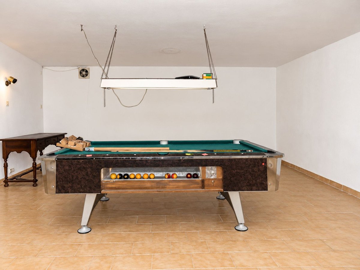 Indoor game room with a pool table, cues, and balls