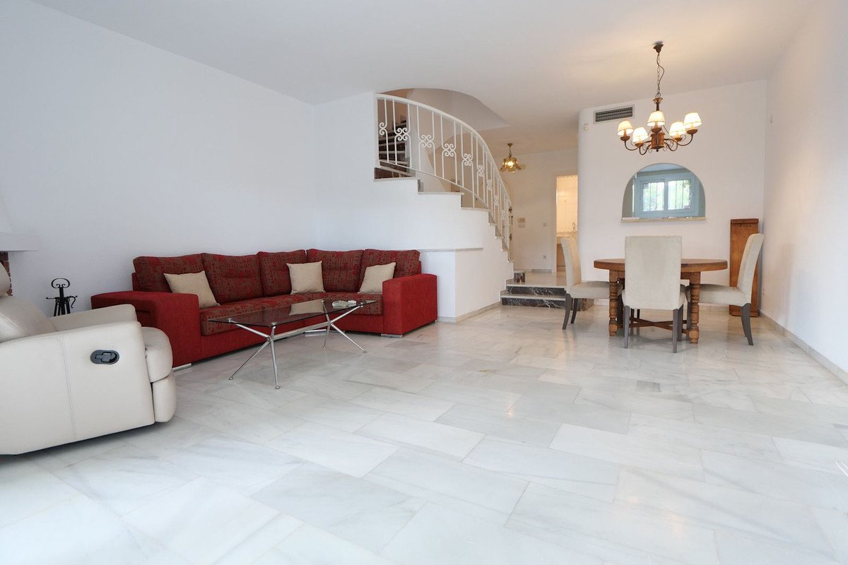 Spacious living room with red sofa, staircase, and dining area with chandelier
