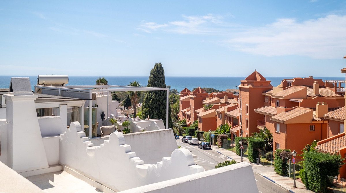 Terrace view overlooking orange apartment buildings and the blue sea under a clear sky.