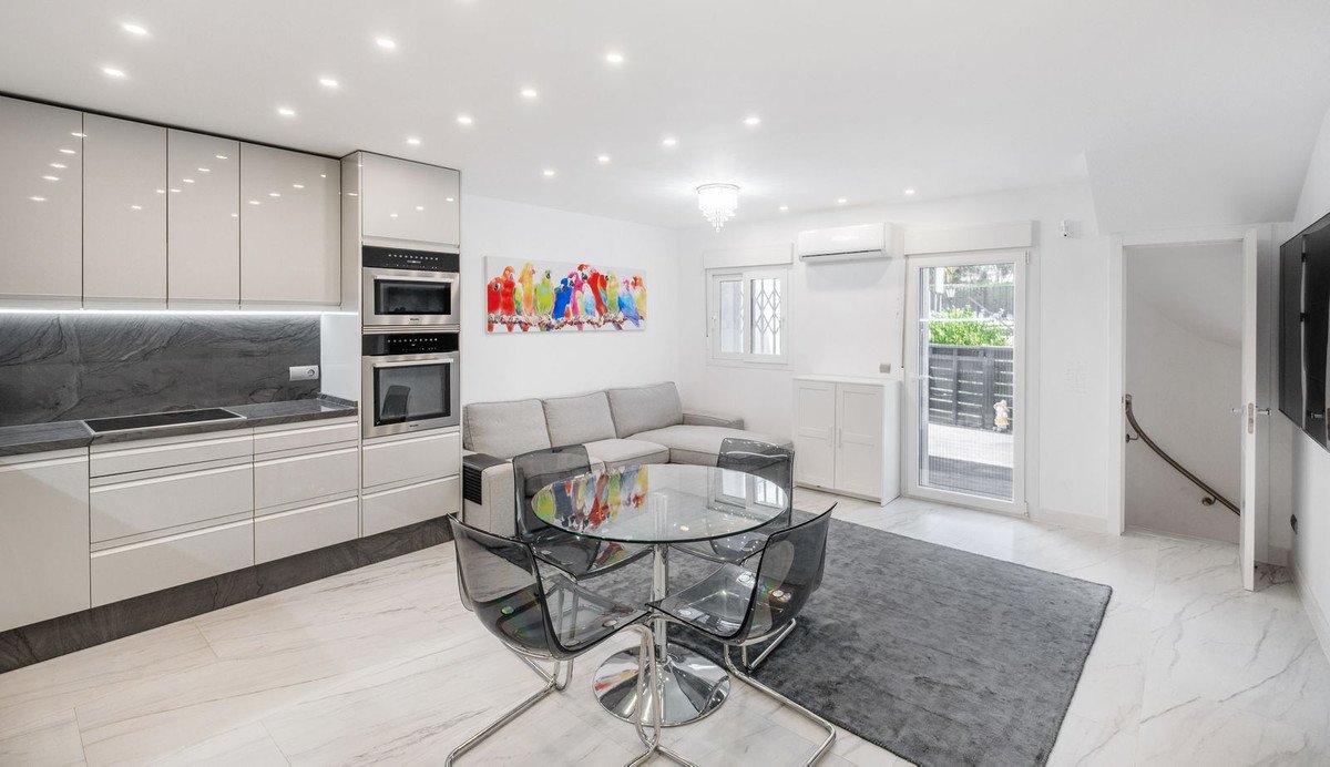 Modern living room with a sectional sofa, sleek kitchen, dining table, and access to an outdoor area outside.