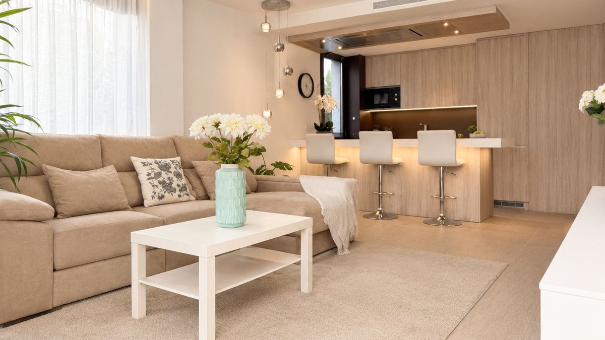 Modern living room with beige sofa, coffee table, and open kitchen view