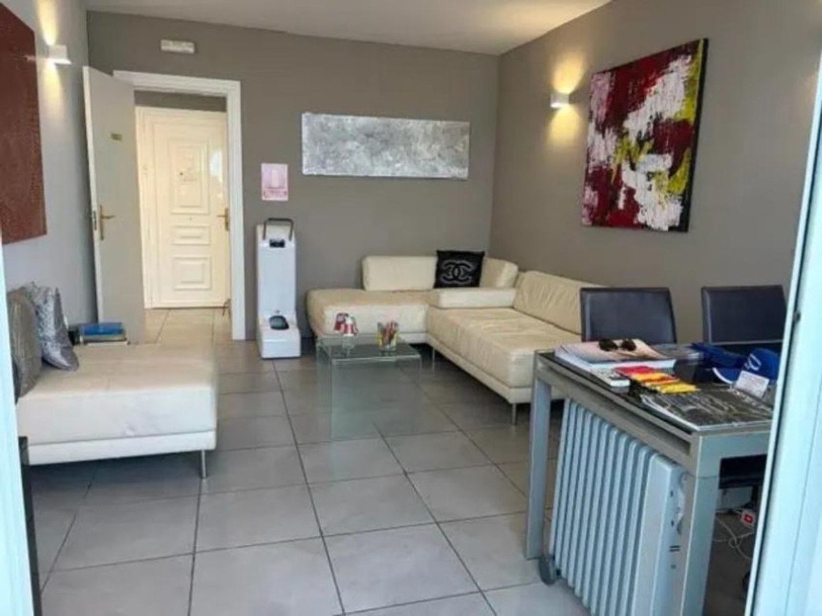 Modern living room with a sectional white sofa, coffee table, desk, and abstract art on a gray wall.
